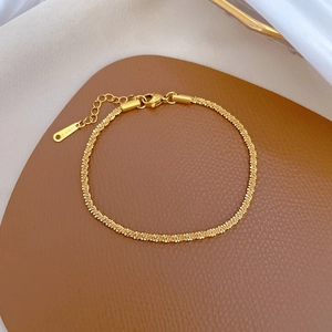 Macro view of golden stainless steel chain bracelet on textured leather and silk