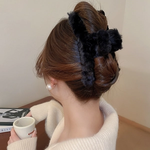 Close-up of black plush cloud cross hair claw clip on dark hair for autumn styling