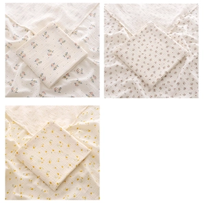 Close-up of three vintage floral muslin cotton baby towels with delicate hemmed edges