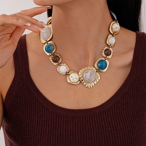 Macro shot of chunky gold necklace with vintage geometric resin stones and hammered metal