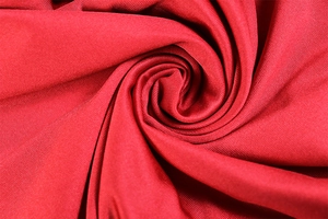 Detailed macro shot of bright red high-elastic knit fabric with smooth textured fibers