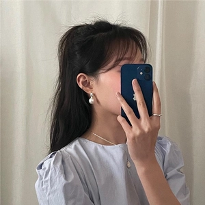 Detail shot of a sweet pearl earring and necklace set worn in a natural mirror selfie