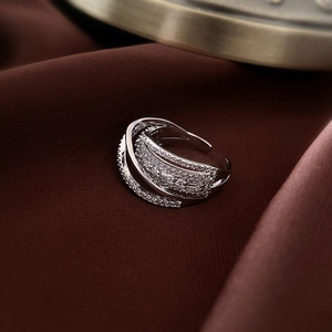 Macro shot of silver multi-layer crisscross ring with white zircons on dark fabric