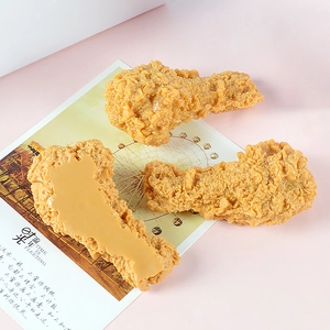 Tre modelli realistici di cosce di pollo fritto in PVC su sfondo rosa con oggetti scena