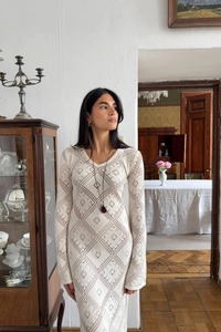 Dettaglio dell'abito lungo in maglia crema con motivi geometrici traforati a rombi