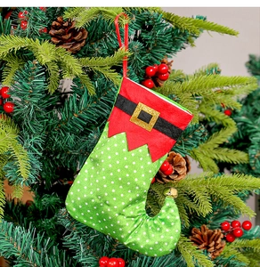 Gros plan d'une chaussette d'elfe de Noël à pois verts avec bord rouge sur un sapin décoré