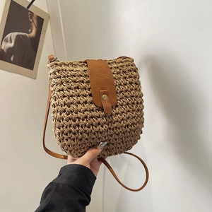 Handwoven straw saddle bag with brown faux leather flap and metal snap for summer beach trips