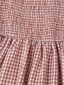 Detailed view of red and white plaid fabric with elastic smocking stitching for a midi dress
