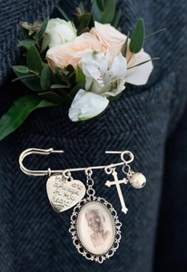 Detail view of memorial photo frame brooch pin with silver heart and cross on suit lapel