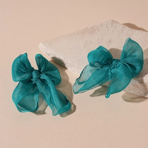 Elegant teal lace bow earrings on a textured stone over a soft neutral background
