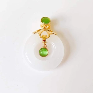 Detail of jade pendant with golden metal mount and sparkling green gemstone accents