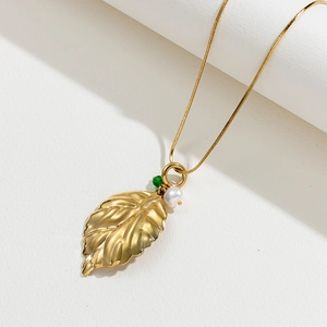 Vue macro d'un pendentif feuille dorée aux nervures détaillées et perle élégante
