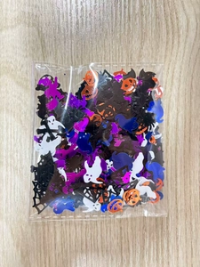Macro detail of mixed Halloween confetti with ghost, pumpkin, and bat shapes in a bag