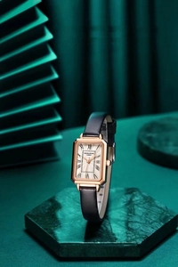 Close-up of an elegant women's rose gold square watch featuring a black leather strap.