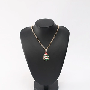Golden Christmas tree pendant necklace with green enamel on a black mannequin display