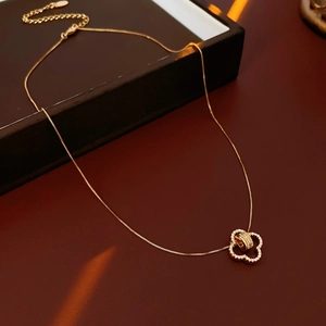 Detail of rose gold clover pendant with crystals on a luxury red velvet background