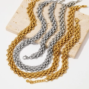 Detail of chunky gold and silver braided stainless steel chain necklaces on stone