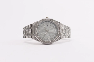 Macro shot of silver iced out octagonal watch with crystal pave dial and calendar window