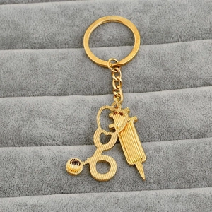 Detail of golden stethoscope and syringe pendants on medical themed metal keychain