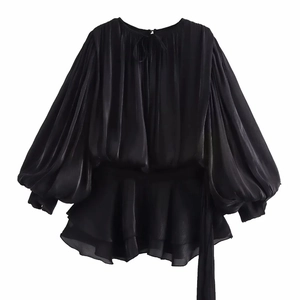 Detail of black satin dress showing elegant lantern sleeves and tiered ruffle hemline