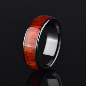 Polished black ring with reddish-brown wood grain inlay on black reflective surface
