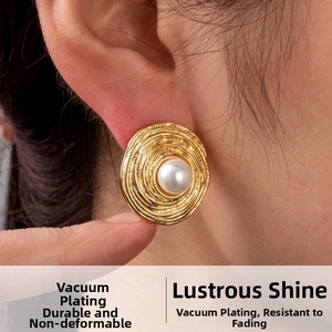 Close-up of golden concentric spiral earrings with white pearl and vacuum plating detail