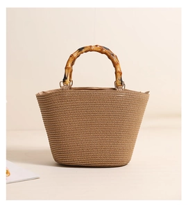 Detailed view of handcrafted woven straw tote featuring signature bamboo top handles
