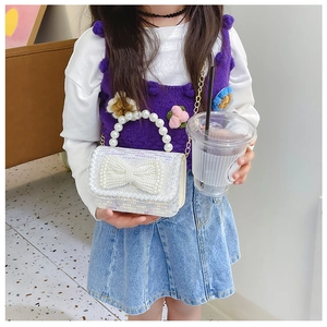 Fillette portant un mini sac blanc à paillettes avec poignée en perles et nœud