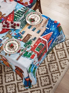 Close-up of Christmas tablecloth featuring winter village, reindeer, and red houses