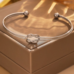 Detail of silver twisted knot steel bracelet on luxury champagne gold jewelry box