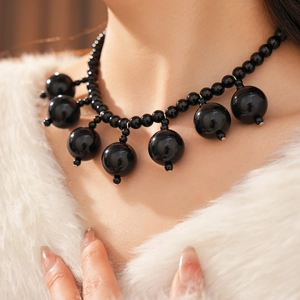 Macro shot of elegant black acrylic beaded necklace with glossy obsidian-like droplets
