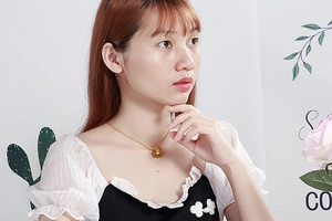 Close-up of golden interlocking double ring pendant necklace worn by a female model