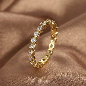 Minimalist gold eternity ring with round cubic zirconia on luxury brown silk fabric