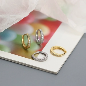 Close-up of gold and silver S925 huggie earrings with sparkling row of cubic zirconia