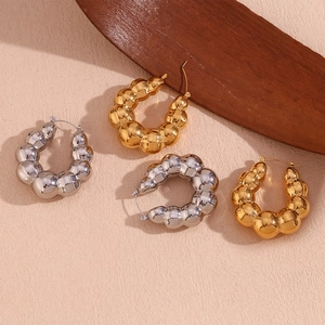 Detailed view of bubble texture hoop earrings in polished gold and silver finishes