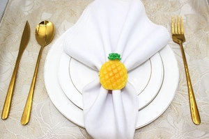 Detailed view of a yellow pineapple napkin ring on a white cloth in a dining setting