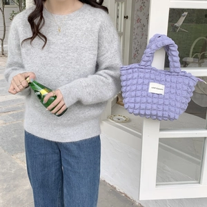 Detail of purple bubble texture canvas handbag with Love Sozakka label on casual knit wear