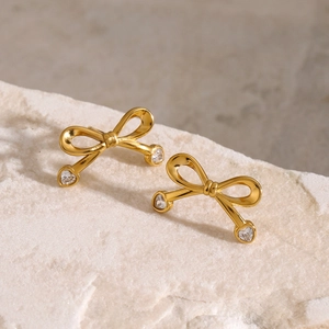 Detailed view of 18k gold plated bow earrings with heart-shaped zircon on stone