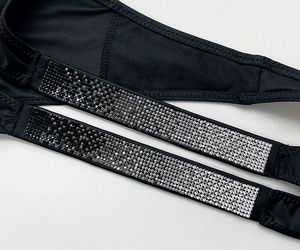 Detailed macro view of sparkling silver rhinestones on black fitness thong fabric