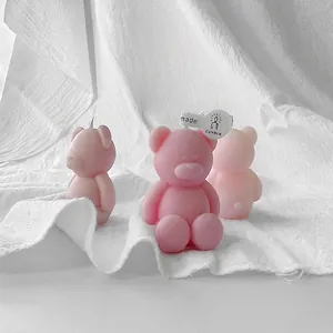 Three mini pink bear scented candles in matte finish on white fabric backdrop