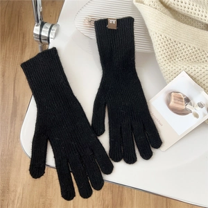 Detail of black knitted gloves with vertical rib texture and small leather logo patch