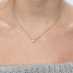 Minimalist gold-plated necklace with a round zircon pendant worn by a model