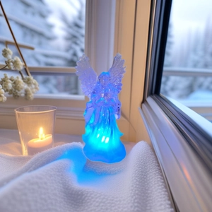 Detail of blue glowing LED acrylic angel figurine placed on a white snowy window sill