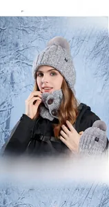 Detail of grey winter knit hat with pompom and buttoned scarf in outdoor snow scene