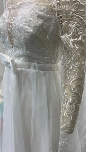 Détail de la broderie en dentelle blanche et des manches en tulle sur une robe de mariée