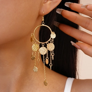 Gros plan de boucles d'oreilles dorées à franges avec disques en métal martelé