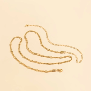 Macro detail of gold layered waist chain with geometric textured squares and lobster clasp