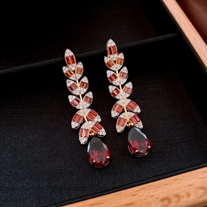 Detail of vintage gold earrings with leaf patterns, red gemstones, and water drop pendants