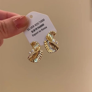 Macro detail of gold twisted shell earrings with zircon accents and S925 silver hallmarks