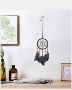 Close-up of black dream catcher with natural feathers and wooden beads on a white wall